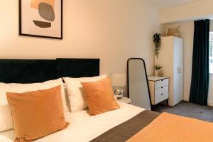 1 dormitorio con 1 cama con almohadas de color naranja en Redhill Apartments by Pay As U Stay en Redhill