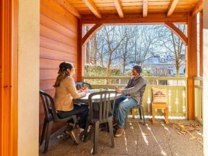 zwei Personen sitzen an einem Tisch auf einer Veranda in der Unterkunft Appartement central à Saint-Lary avec piscine, sauna et parking sécurisé - FR-1-296-398 in Saint-Lary-Soulan