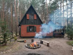 una cabaña con fuego delante de ella en Domek Leśny Klimat, en Serpelice