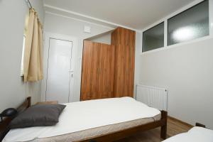 een slaapkamer met een wit bed en een houten kast bij Premier apartments in Kladovo
