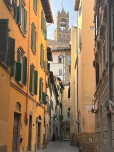 een steegje met gebouwen en een klokkentoren in de verte bij Corno in Florence