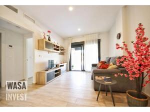 a living room with a couch and a tree in it at Pinada Beach IV new & comfort. apartment, 1st line to the beach, sunterrace+pool in La Mata