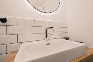 lavabo blanco en el baño con espejo en Einzimmerwohnung in Seenähe klimatisiert, en Friedrichshafen