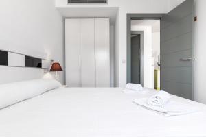 a white bedroom with a large bed with towels on it at Las Hélices San José Cabo de Gata in San José