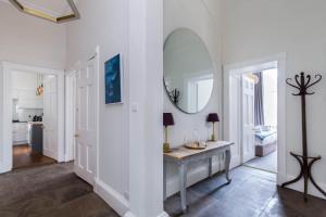 a white hallway with a table and a mirror at Magnificent Georgian 3-Bedroom Apartment in New Town in Edinburgh