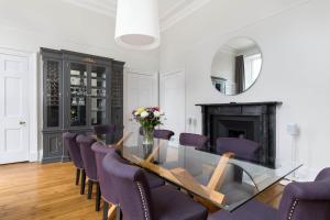 a dining room with a glass table and purple chairs at Magnificent Georgian 3-Bedroom Apartment in New Town in Edinburgh