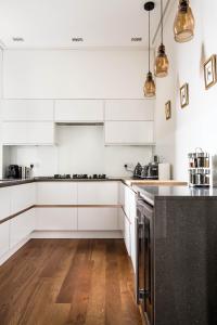a white kitchen with wooden floors and white cabinets at Magnificent Georgian 3-Bedroom Apartment in New Town in Edinburgh