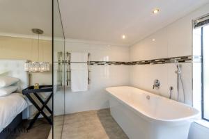 baño blanco con bañera y cama en The Jewel B&B, en Ciudad del Cabo