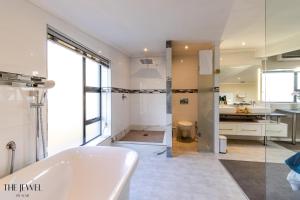 Cape Town的住宿－The Jewel B&B，白色的浴室设有浴缸和水槽。
