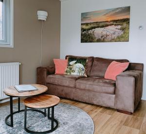 a living room with a brown couch and a table at 4p chalet TOLVE met 4 fietsen vlakbij natuurgebieden Drents Friese Wold, Fochteloërveen en gevangenisdorp Veenhuizen in Oosterwolde