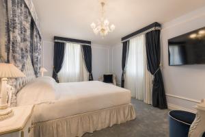 a bedroom with a white bed and a chandelier at Grand Hotel Principe Di Piemonte in Viareggio