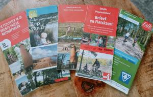 a bunch of brochures sitting on a table at 4p chalet TOLVE met 4 fietsen vlakbij natuurgebieden Drents Friese Wold, Fochteloërveen en gevangenisdorp Veenhuizen in Oosterwolde