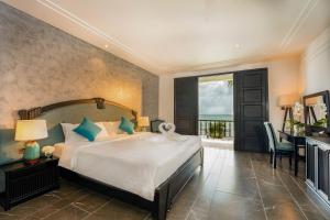 a bedroom with a bed and a desk and a window at Dankbaar Resort Quy Nhon in Quy Nhon