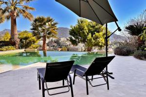 two chairs and an umbrella in front of a pool at La Villa Gairaut in Nice