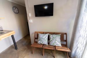 a bench with two pillows on it with a television on a wall at Mulkana in Bloemfontein