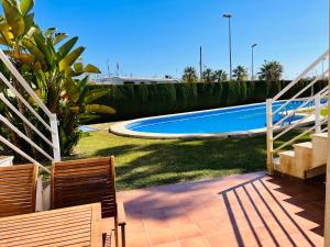 a swimming pool in a yard with two chairs at Apartamento Rabdells Olivanova 150m de la playa in Oliva