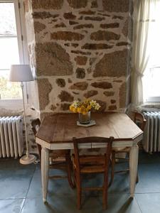 uma mesa de madeira com um vaso de flores em Chambre indépendante - style studio - avec jardin à la campagne em Junhac