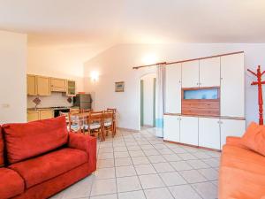 sala de estar con sofá rojo y cocina en Cala Francese Apartments, en Capo Testa