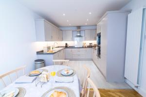 a kitchen with a table and chairs and a kitchen with white cabinets at Mulberry Cottage - Cosy 3 Bed Cottage near Lytham Windmill in Lytham St Annes