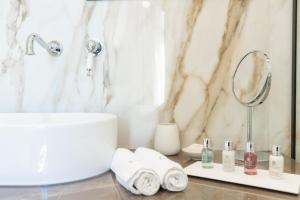 La salle de bains est pourvue d'un lavabo, d'un miroir et de serviettes. dans l'établissement EPICURE SUITES, à Kavala