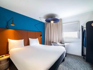 una habitación de hotel con una gran cama blanca y una ventana en ibis Paris porte de Bercy, en Charenton-le-Pont