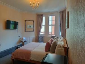 a bedroom with a bed with a television and a window at Kingsholm Guest House in Torquay