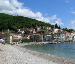 a group of people sitting on a beach near the water at Apartman Modric Draga in Mošćenička Draga