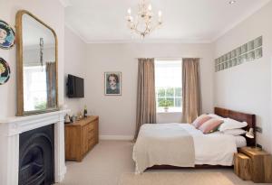 a bedroom with a bed and a fireplace and a mirror at Rame Barton Guest House and Pottery in Cawsand