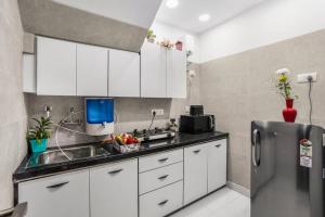 a kitchen with white cabinets and a sink and a refrigerator at Homlee-Basement Flat with kitchen in Saket, South Delhi in New Delhi