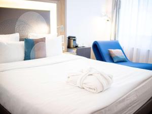 sypialnia z białym łóżkiem i niebieskim krzesłem w obiekcie Novotel Krasnoyarsk Center w Krasnojarsku