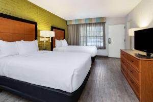 a hotel room with two beds and a flat screen tv at La Quinta Inn Tampa Airport Stadium Westshore in Tampa