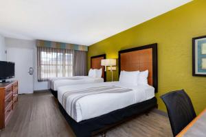 a hotel room with two beds and a television at La Quinta Inn Tampa Airport Stadium Westshore in Tampa