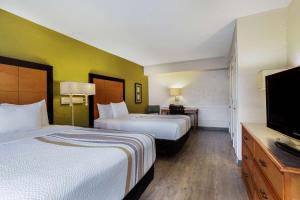 a hotel room with two beds and a flat screen tv at La Quinta Inn Tampa Airport Stadium Westshore in Tampa