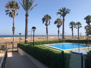 una piscina con palmeras y la playa en ATICO EN PRIMERA LÍNEA MEDITERRANEO, en Peñíscola