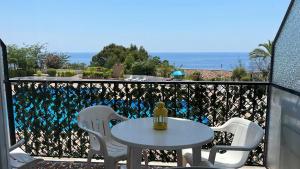 una mesa y sillas en un balcón con vistas al océano en Studios LES TERRASSES de Cala Llevado en Tossa de Mar
