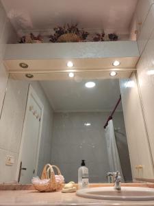 lavabo en el baño con un espejo grande encima. en La casa de la Plaza - WIFI - Barbacoa - Chimenea, en Cirueña