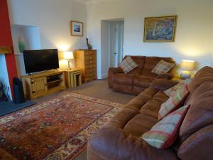 a living room with a couch and a flat screen tv at Shelduck Cottage in Mainsriddle
