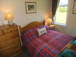a bedroom with a bed and a dresser and two lamps at Shelduck Cottage in Mainsriddle