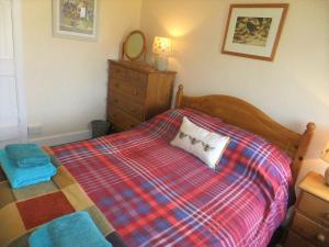 a bedroom with a bed with a plaid blanket at Shelduck Cottage in Mainsriddle