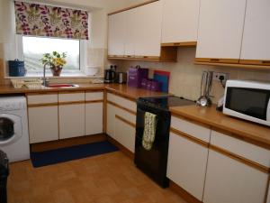 a kitchen with white cabinets and a black stove top oven at Shelduck Cottage in Mainsriddle +17 photos