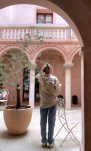 una mujer de pie junto a un plantador en un edificio en Hotel Palau Macelli en Castellón de Ampurias