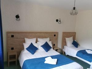 a bedroom with two beds with blue and white pillows at Auberge Du Riou in Puget-Rostang