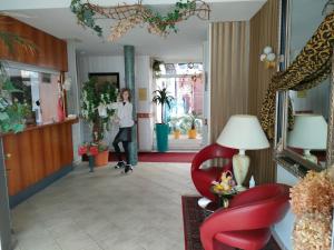 una mujer parada en un pasillo con una silla roja en Hotel Haegert, en Neustrelitz