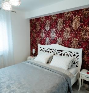 a bedroom with a bed and a red wall at Carla's Apart Palas-Hala Centrala 1 Bedroom - shuttle in Iaşi