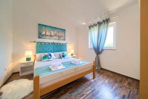 a bedroom with a bed with a blue headboard and a window at Apartment TOP in Kornić