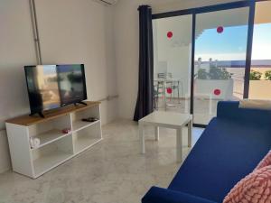 ein Wohnzimmer mit einem TV und einem blauen Sofa in der Unterkunft Wohnung Sabina in Agüimes