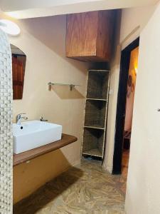 a bathroom with a white sink and a shelf at Bamboo Village Resort in Kololi