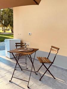 una mesa de madera y una silla con copas de vino en el patio en Agricampeggio La Piaggia - Agriturismo en Piombino