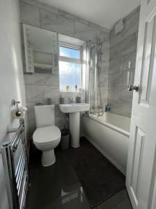 a bathroom with a toilet and a sink and a tub at Modern 4-bed house with garden & parking in Walsgrave on Sowe