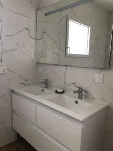 bagno bianco con lavandino e specchio di Chez Yolande a Lampaul-Plouarzel